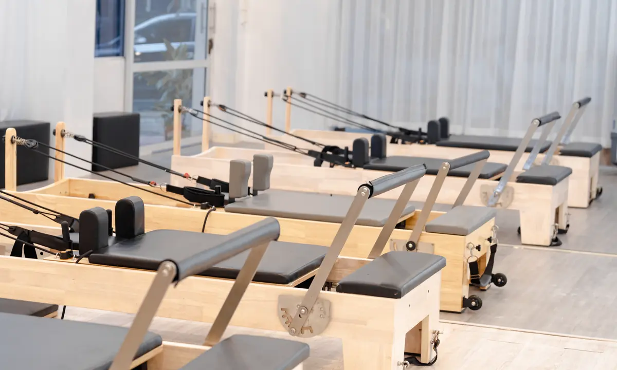 Lichte pilatesstudio met een rij houten reformers