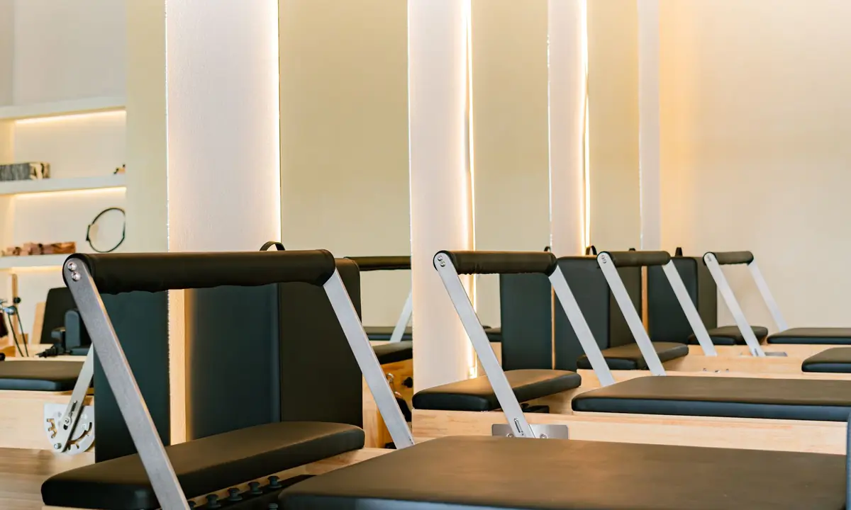 Lichte pilatesstudio met een rij reformers